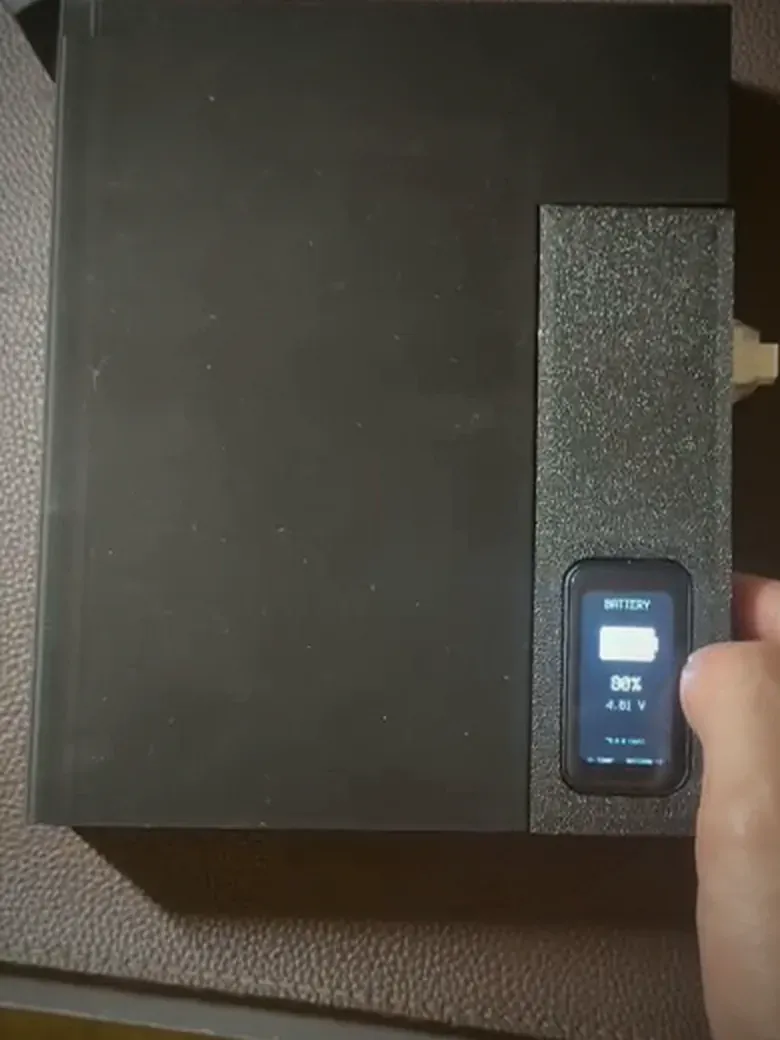 The Phone Box: a dark textured enclosure with a small portrait touchscreen showing the battery percentage.